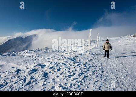 Mann in den Sechzigern im Winter in Karkonosze (Riesengebirge) wandern, Föhn Wolke, Sudetengebirge, Nationalpark Karkonosze, Niederschlesien, Polen Stockfoto