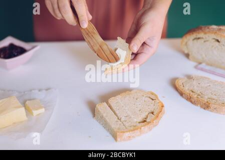 Womans Hand streut Butter auf hausgemachtem Brot Stockfoto