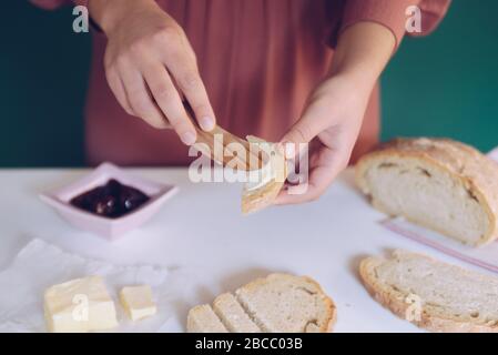 Womans Hand streut Butter auf hausgemachtem Brot Stockfoto