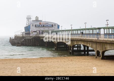 Bournemouth, Dorset UK. April 2020. Wetter in Großbritannien: Nebeliger Morgen in Bournemouth, da die Besucher rieten, zu Hause zu bleiben und sich an die Einschränkungen von Coronavirus für soziale Distanzierungen zu halten, wobei Parkplätze geschlossen sind, um Besucher abzuschrecken, die aus der Ferne fahren. Die Strände sind hauptsächlich leer, abgesehen von denen, die das Meer besuchen, um ihre erlaubten Übungen zu machen. Die Botschaft ist deutlich sichtbar durch den Nebel am Bournemouth Pier, der geschlossen ist - zu Hause zu bleiben. Credit: Carolyn Jenkins/Alamy Live News Stockfoto