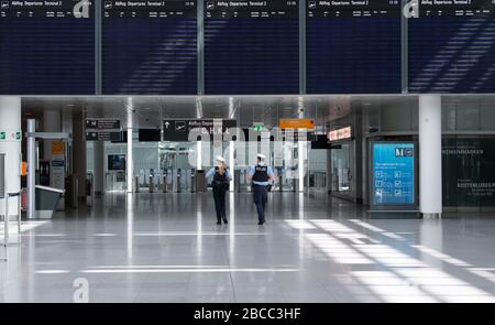 München, Deutschland. April 2020. Zwei Polizisten laufen durch das ansonsten fast menschenleere Terminal des Flughafens München. Durch die Corona-Pandemie ist der Flugverkehr praktisch zum Erliegen gekommen. Credit: Sven Hoppe / dpa / Alamy Live News Stockfoto