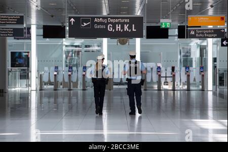 München, Deutschland. April 2020. Zwei Polizisten laufen durch das ansonsten fast menschenleere Terminal des Flughafens München. Durch die Corona-Pandemie ist der Flugverkehr praktisch zum Erliegen gekommen. Credit: Sven Hoppe / dpa / Alamy Live News Stockfoto