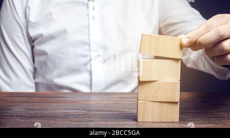 Der Geschäftsmann stellt Holzklötze. Risikomanagement. Konzept des Business Managements. Planung und Strategie. Ziele setzen und erreichen. Leistung. Stockfoto