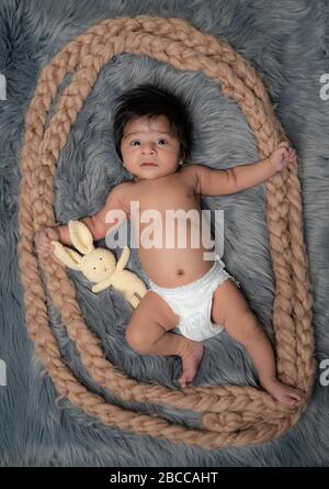 Neugeborenes Baby und sein erstes Spielzeug Teddybär liegen auf dem Pelzbett Stockfoto