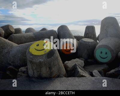 Betonsteine am Strand mit bunten Gesichtern dekoriert. Stockfoto