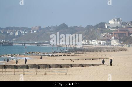 Die Menschen gehen an einem einsamen Strand von Boscombe entlang, während Großbritannien weiterhin in Sperrungen bleibt, um die Ausbreitung des Coronavirus einzudämmen. Stockfoto