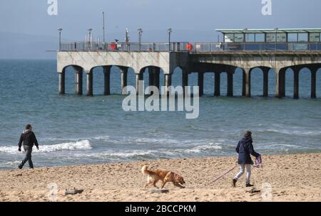 Die Menschen gehen an einem einsamen Strand von Boscombe entlang, während Großbritannien weiterhin in Sperrungen bleibt, um die Ausbreitung des Coronavirus einzudämmen. Stockfoto