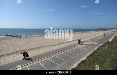 Die Menschen gehen an einem einsamen Strand von Boscombe entlang, während Großbritannien weiterhin in Sperrungen bleibt, um die Ausbreitung des Coronavirus einzudämmen. Stockfoto