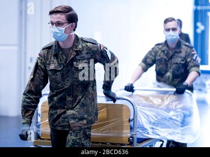 Hannover, Deutschland. April 2020. Soldaten, die Gesichtsmasken tragen, bringen Krankenhausbetten in die provisorische Klinik auf dem Messegelände, die am selben Tag von Ministerpräsident weil besucht wurde. Die Maßnahmen zur Eindämmung des Virus zeigen derzeit weniger Wirkung als gewünscht. Kredit: Peter Steffen / dpa / Alamy Live News Stockfoto