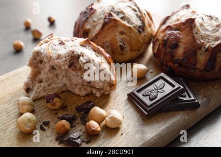 Zerbrochene Brötchen mit Nüssen und Schokolade auf einem Schneidebrett Nahansicht. Hausgemachtes Gebäck Stockfoto