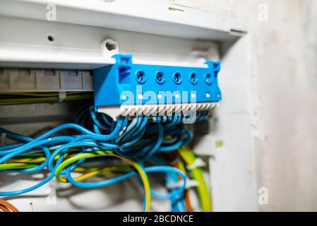 Blauer selbstsichernde Block für neutrale elektrische Leitungen, montiert in der Elektrobox mit angeschlossenen Kabeln. Stockfoto