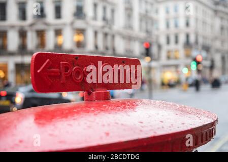 Rotes englisches Postfach, das einen Brief in einer belebten Londoner Straße sendet. Stockfoto