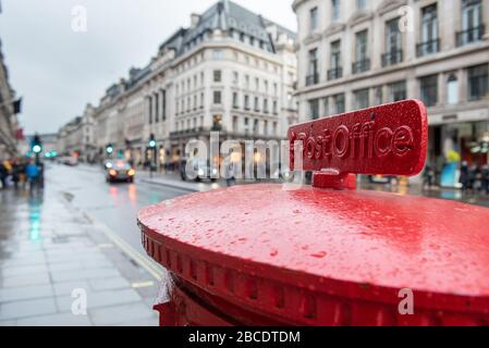 Rotes englisches Postfach, das einen Brief in einer belebten Londoner Straße sendet. Stockfoto