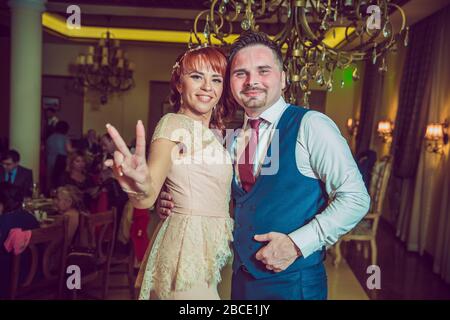 Der Bräutigam hält die Hand der Frau, die mitten in einem Restaurant mit ihr tanzt. Nur ein Ehepaar tanzt .romantische Paare von Neuvermählten tanzen auf der Hochzeit Stockfoto