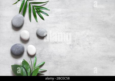 Grauer Spa-Hintergrund, Spa-Konzept, Palmblätter und graue Steine, Draufsicht. Stockfoto