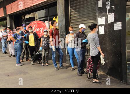 Caracas, Venezuela 31. März 2020: Menschen, die Schutzmasken tragen, die auf Linien stehen und auf Kurven warten, um während der Quarantänekrise einen Supermarkt zu betreten Stockfoto