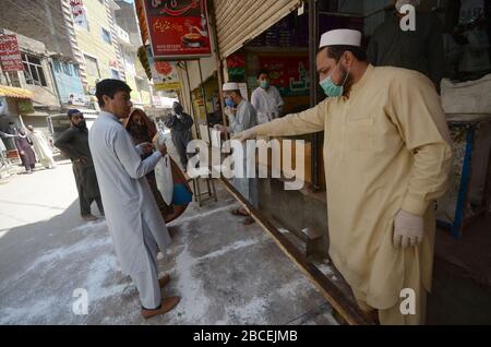 Peschawar, Pakistan. April 2020. Menschen stehen in der Ferne, um während einer landesweiten Sperre Lebensmittel zu kaufen, um den Ausbruch des Corona-Virus zu verhindern (Foto von Hussain Ali/Pacific Press) Kredit: Pacific Press Agency/Alamy Live News Stockfoto