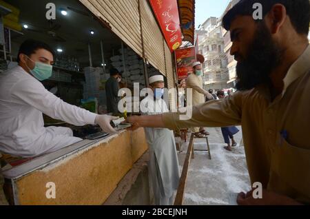 Peschawar, Pakistan. April 2020. Menschen stehen in der Ferne, um während einer landesweiten Sperre Lebensmittel zu kaufen, um den Ausbruch des Corona-Virus zu verhindern (Foto von Hussain Ali/Pacific Press) Kredit: Pacific Press Agency/Alamy Live News Stockfoto