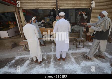 Peschawar, Pakistan. April 2020. Menschen stehen in der Ferne, um während einer landesweiten Sperre Lebensmittel zu kaufen, um den Ausbruch des Corona-Virus zu verhindern (Foto von Hussain Ali/Pacific Press) Kredit: Pacific Press Agency/Alamy Live News Stockfoto