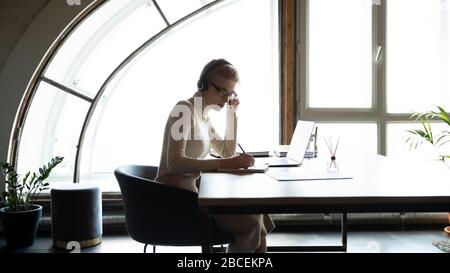 Konzentrierter Leiter, der am Tisch sitzt und Online-Treffen mit Kollegen abhält. Stockfoto