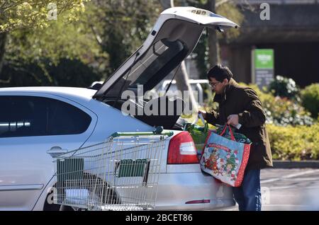 Ein Mann, der Lebensmittel in den Kofferraum seines Autos in einem Supermarkt-Parkplatz in Großbritannien legt Stockfoto