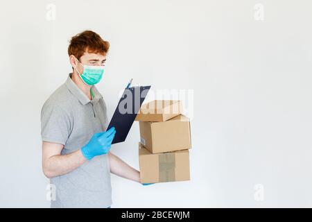 Kurier liefert Karton in chirurgischen Handschuhen und chirurgischen Masken. Sicherheitspost, der während der Epidemie geliefert wird. Kuriermann mit Päckchen über Whi Stockfoto