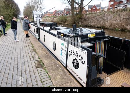 Leute, die Essen (Staffordshire Haferkuchen) von einem Schmalboot ()que Sara Sara, dem B'Haferkuchen Boot) an einem Kanal, Stoke-on-Trent, Staffordshire, Großbritannien kaufen Stockfoto