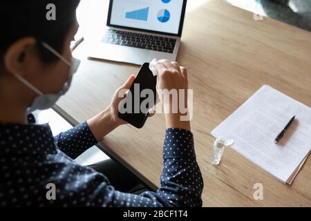 Junge inderin wischt Smartphone-Bildschirm mit antibakterieller Serviette. Stockfoto