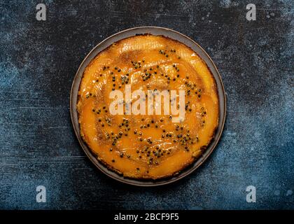 Hausgemachte Mango-Kuchen auf dem Kopf mit Passionsfrucht auf einem dunklen rustikalen Hintergrund. Köstliches vegetarisches Süßspeisen-Konzept. Horizontale Ansicht von abov Stockfoto