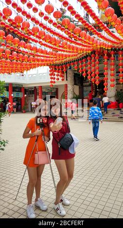 Zwei junge chinesische Mädchen fotografieren in einem traditionellen chinesischen Tempel. Neujahrsfeier Stockfoto