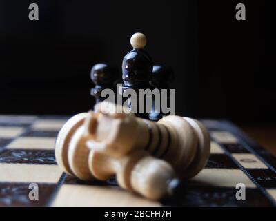 Weiße und schwarze Holzkitze stehen auf dem hölzernen Schachtisch mit Bokeh, Sieg, Sieg, Stockfoto