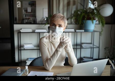 Verantwortungsbewusste Geschäftsfrau in Facemask und medizinische Handschuhe mit Blick auf die Kamera. Stockfoto