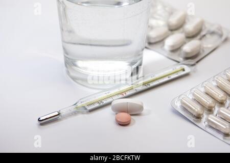 Pillenpackungen, Industitialthermometer mit bunten Medikamenten auf weißem Hintergrund, Tisch, Heilung, Impfstoff, Medikamente, erste Hilfe Stockfoto