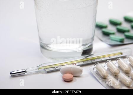 Pillenpackungen, Industitialthermometer mit bunten Medikamenten auf weißem Hintergrund, Tisch, Heilung, Impfstoff, Medikamente, erste Hilfe Stockfoto