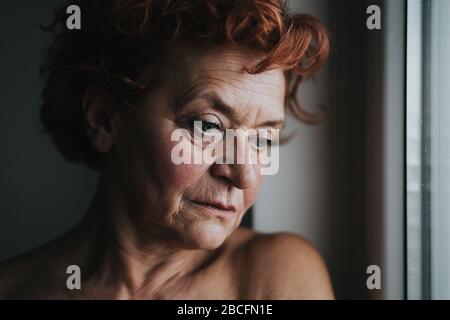 Frau am Fenster, die über das Leben nachdenkt Stockfoto