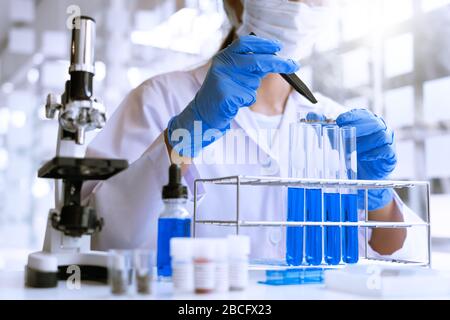 Wissenschaftler, die im Labor im weißen Labormantel recherchieren, Handschuhe analysieren, Reagenzgläser Probe betrachten, Biotechnologiekonzept. Stockfoto