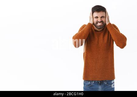 Portrait des ärgerlichen bärtigen Kerls, der während der Kovid19-Pandemie von zu Hause aus arbeitet, verschlagene Ohren und klammende Zähne gereizt sind, beschweren sich über spielende Nachbarn Stockfoto
