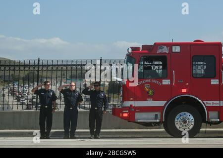 Riverside, Kalifornien, USA. April 2020. Feuerwehrleute stehen auf ihrem Feuerwehrauto, um der vorbeifahrenden Prozession des Körpers von David Werksman auf der Interstate 15, Freitag, 3. April 2020, in Corona, Kalifornien, zu Ehren zu kommen. Riverside County Sheriff Chad Bianco gab zuvor die Verabschiedung des stellvertretenden David Werksman bekannt, der an Komplikationen des Romans COVID-19 starb. Werksman ist der zweite Mitarbeiter des County Sheriffs, der aufgrund des Coronavirus starb. (Foto von IOS/Espa-Images) Credit: European Sports Photographic Agency/Alamy Live News Stockfoto