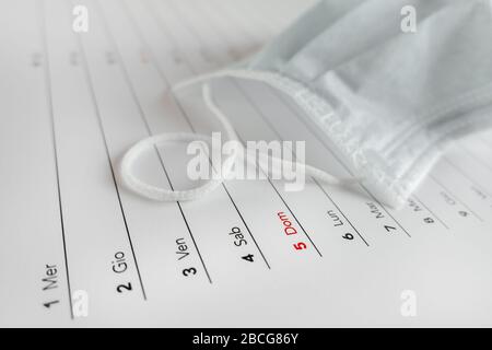 Montler Kalender mit Gesichtsmaske zum Selbstschutz. Coronavirus Konzept. Beginn/Ende der Pandemie. Terminkonzept mit Blatt Monatskalender. Stockfoto