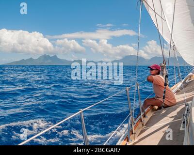 Junge Frau auf einer Segelyacht, nähert sich der Insel Raiatea vom Meer, Französisch-Polynesien, Gesellschaftsinseln, südpazifik Stockfoto