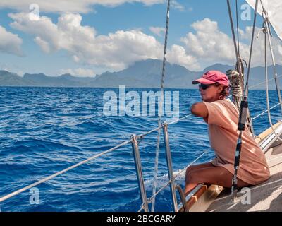 Junge Frau auf einer Segelyacht, nähert sich der Insel Raiatea vom Meer, Französisch-Polynesien, Gesellschaftsinseln, südpazifik Stockfoto