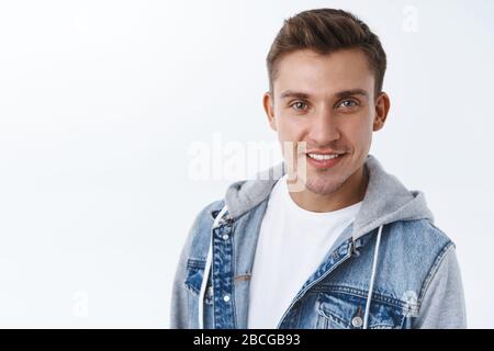 Nahaufnahme des gutaussehenden sassigen, selbstbewussten Schwulen mit strahlendem Lächeln, blondem Haar und blauen Augen, Kamera bestimmt und stolzes Gefühl während Stockfoto