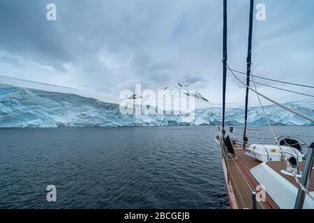 Segelboot in der Antarktis, Yacht-Navigation durch Eisberge und Meereis. Stockfoto