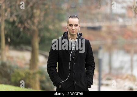 Gutaussehender Mann, der Ohrhörer im Public Park hört Stockfoto
