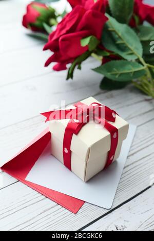Nahaufnahme von Geschenkbox, Umschlag und Rosenblüblume auf dem Tisch. Stockfoto