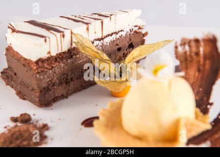 Dreischokoladenkuchenplatte mit einer Schaufel Vanilleeis und einer Physalis. Stockfoto