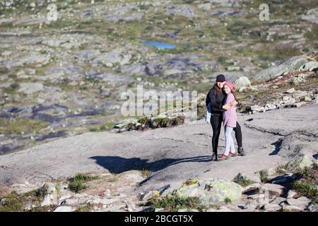 Mutter umarmte die Tochter im Teenager-Alter und stand auf dem Felsen, während sie zu Trolltunga, Copyspace, ging. Norwegen, Europa Stockfoto