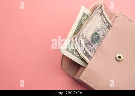 Nahaufnahme des US-Dollars in einer Frauen-Brieftasche auf pinkfarbenem Hintergrund. Stockfoto