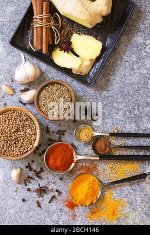 Auswahl an indischen Gewürzen und Kräutern auf einem Steintisch. Flacher Laienhintergrund in der Draufsicht. Stockfoto