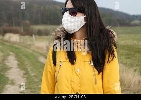 Die Frau trägt die selbstgemachte Textilmaske als Schutz gegen die Übertragung der Viren wie Coronavirus. Sie trägt es sogar in der Natur. Stockfoto